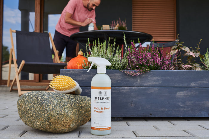 Delphis patio and stone cleaner bottle on a patio with plants and a person in the background